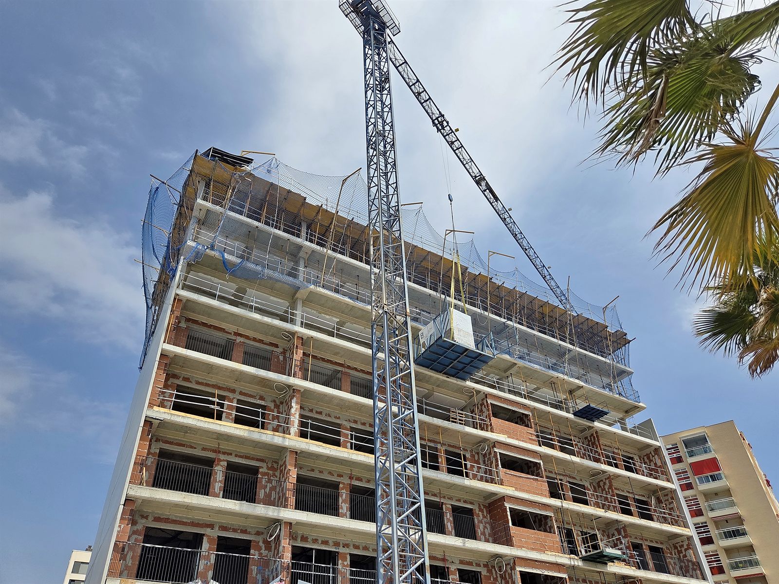 Grúa izando un baño industrializado hasta la planta de un edificio residencial en obra