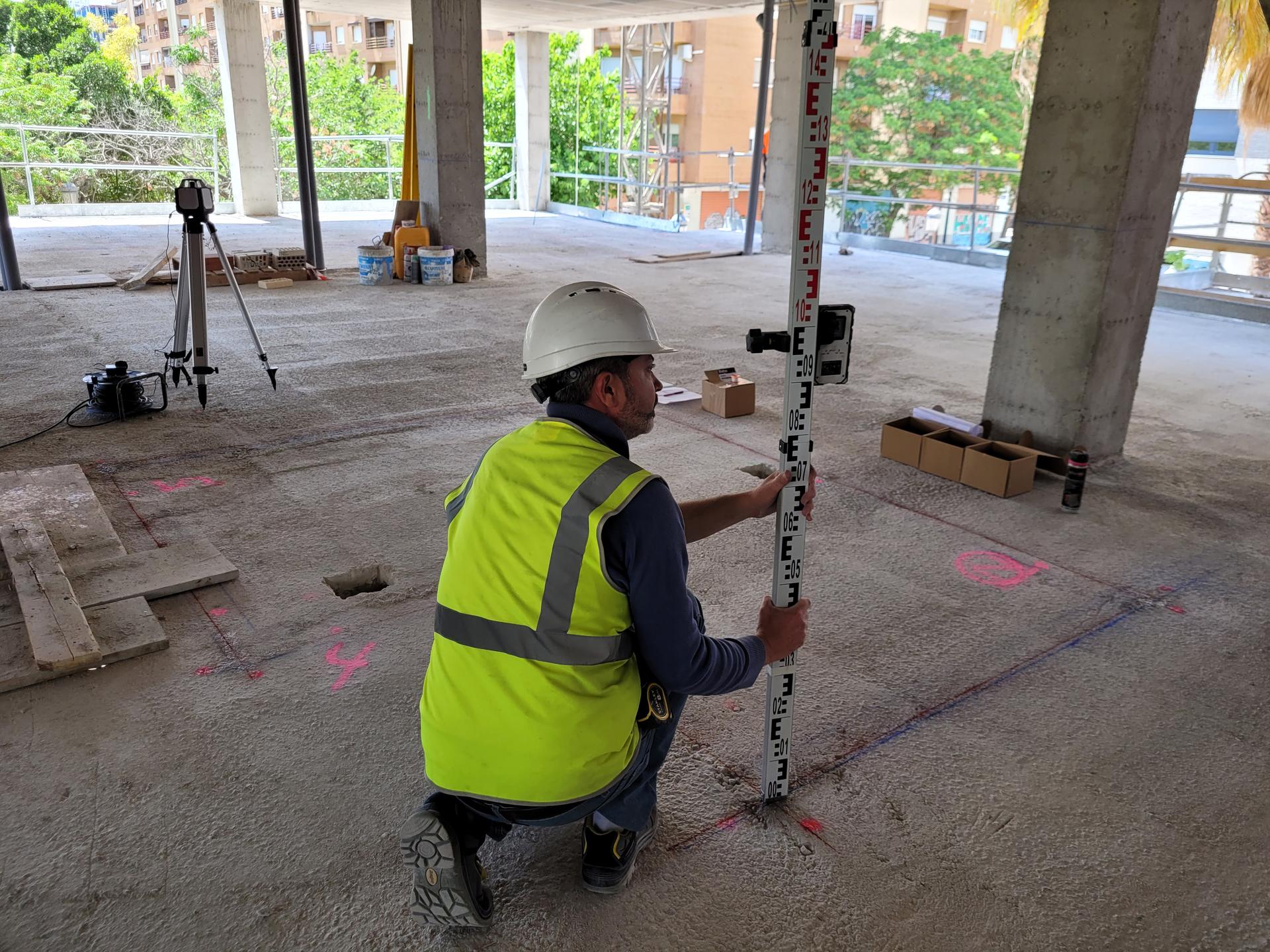Operario realizando el replanteo topográfico de la planta antes del montaje de los baños industrializados