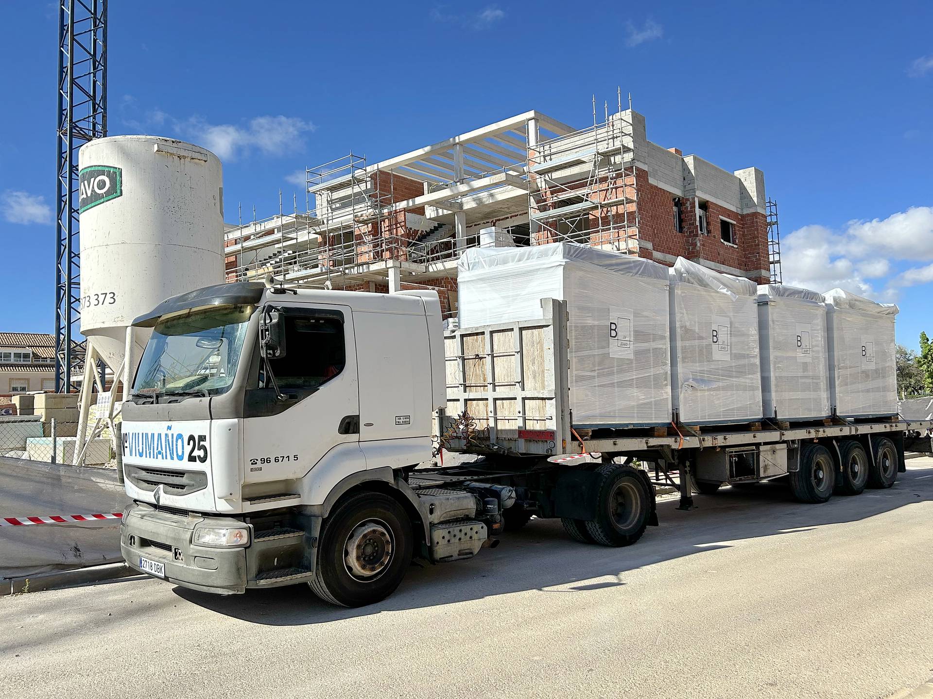 Camión con baños industrializados embalados llegando a una obra residencial