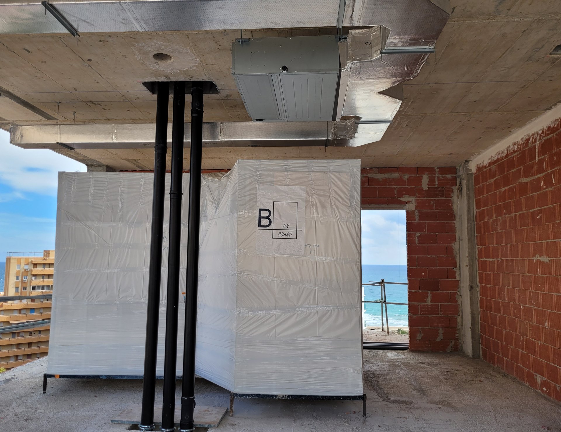 Baños industrializados embalados colocados en planta junto a las bajantes del edificio, antes del cierre de fachada